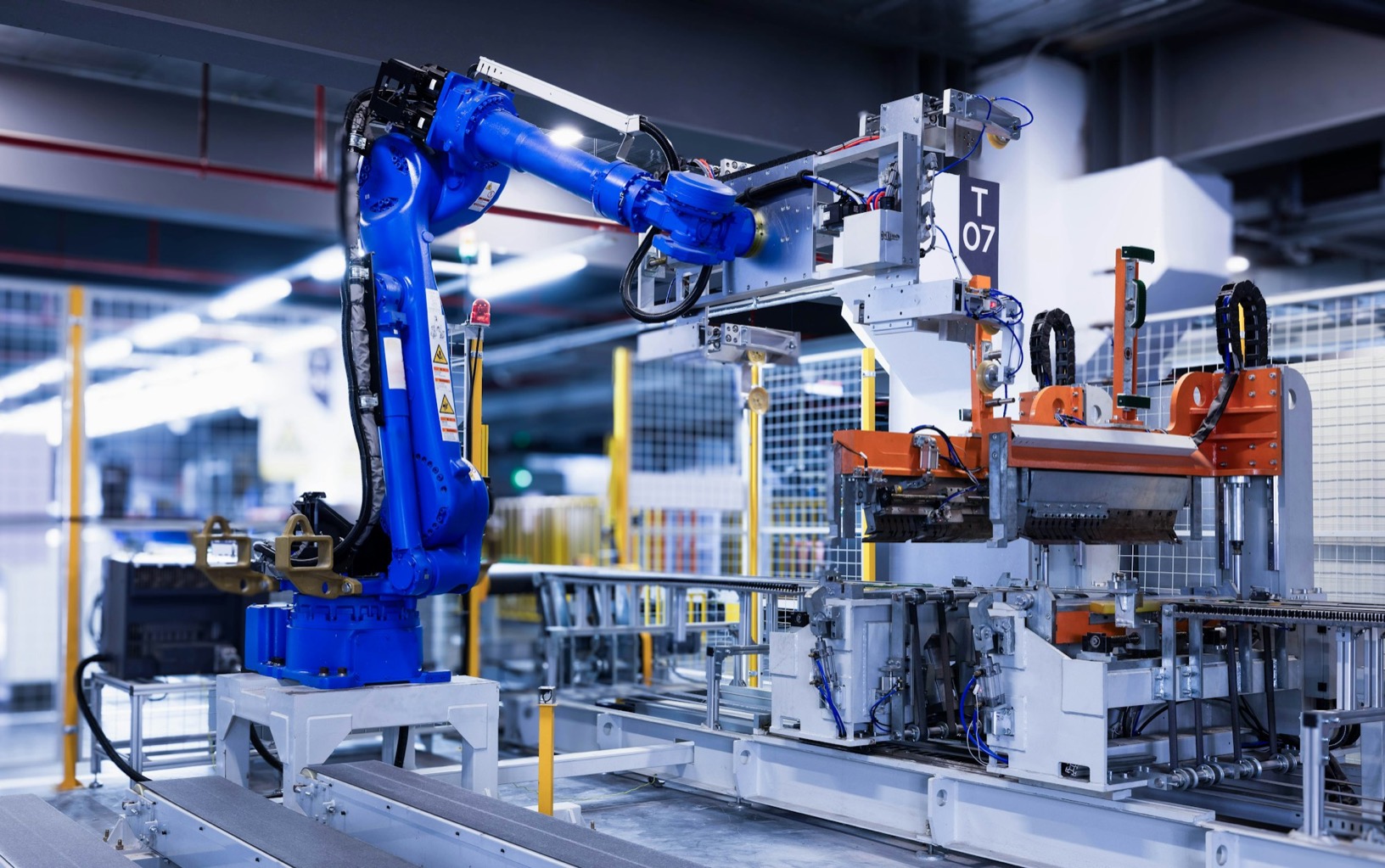 A blue robot arm working on an automated production line in a factory.